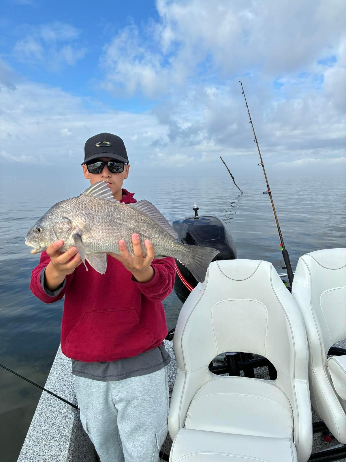 Angler holding a large black drum on open water